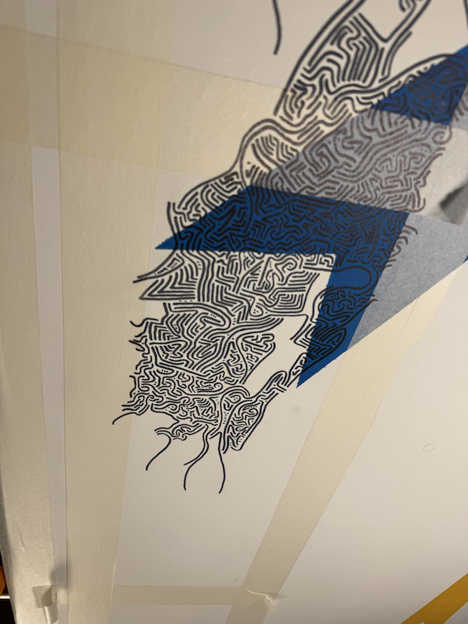 Process view of black mural detail crossing a blue geometric shape