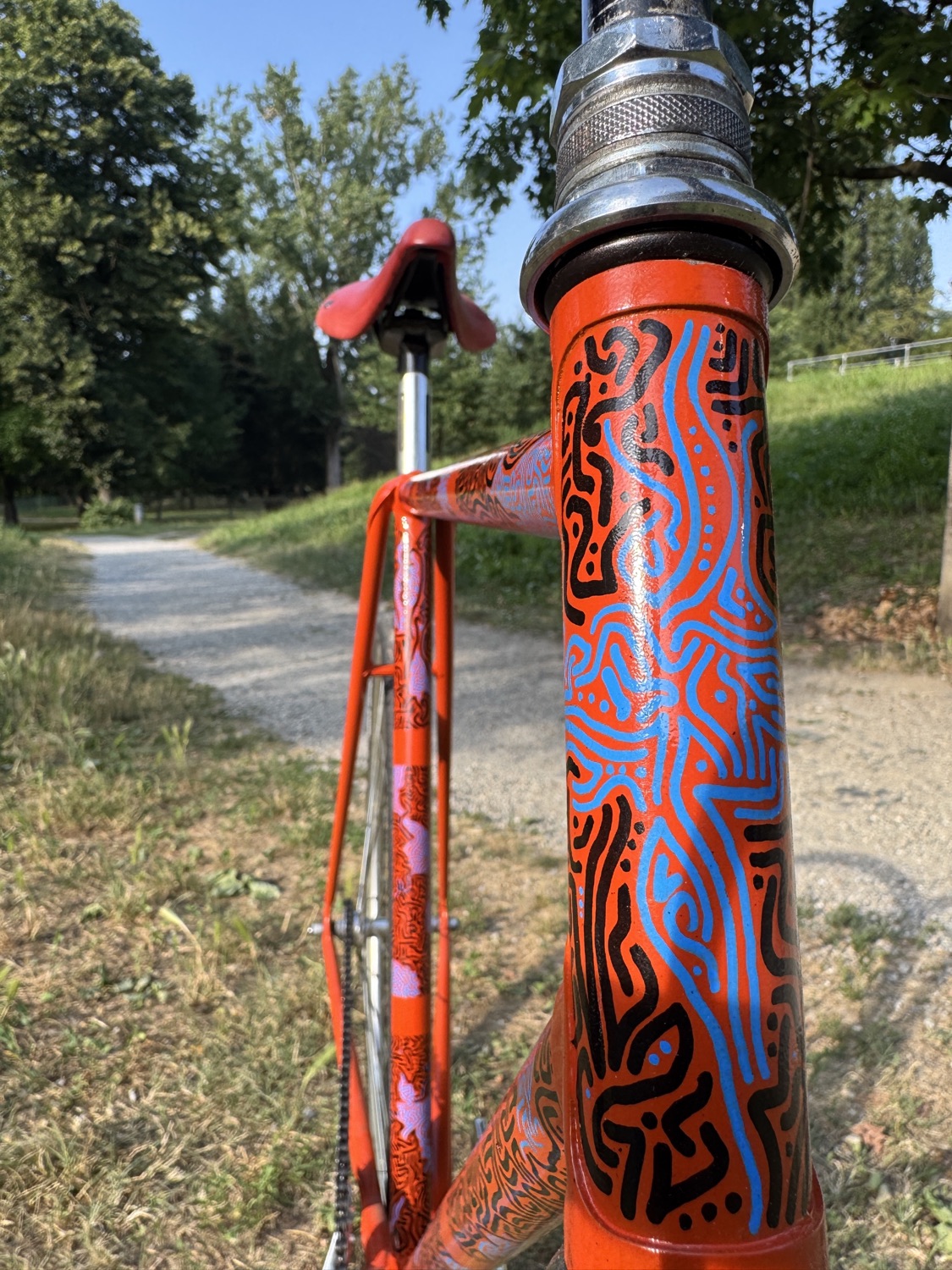 Close view of intricate black and blue marks on the orange bicycle head tube