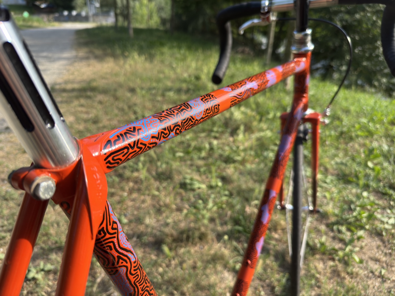 Painted linework along the top tube of the orange bicycle